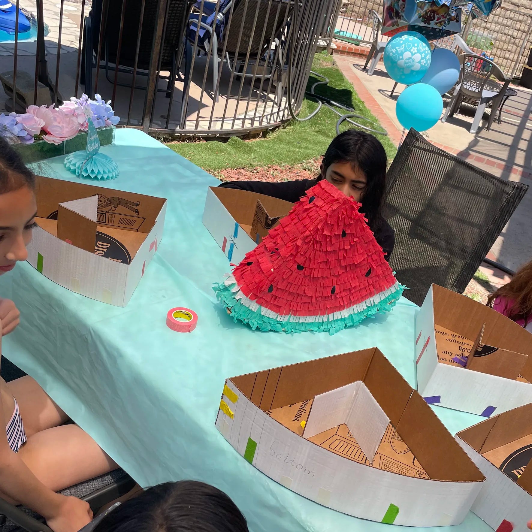 Kids creating a watermelon piñata craft during an outdoor birthday party activity in Los Angeles
